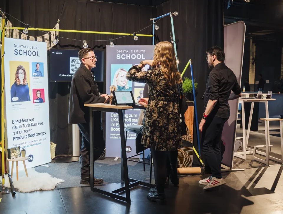 DL-School-Stand 2024 mit Bannern „Beschleunige deine Tech-Karriere mit unseren Product Bootcamps“, Beratung am Stehtisch (Partner-Banner links weggeschnitten)